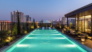 A rooftop swimming pool with a cityscape view, lounge chairs, and a covered seating area. - Kunming Kasion Hotel (Kunming)