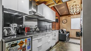A modern kitchen with stainless steel appliances, a brick accent wall, and a clock on the wall. - Alpine Haven 6 - Mt Hotham (Hotham Heights)