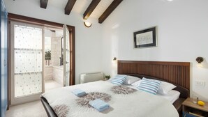 Een slaapkamer met een bed, een nachtkastje, een wandlamp, een lijst met een foto en een schuifdeur naar een buitenruimte.