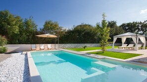 Una piscina con sillas de descanso y un pabellón.