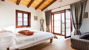 Quarto com cama, janela, porta que dá para o exterior e uma cadeira.