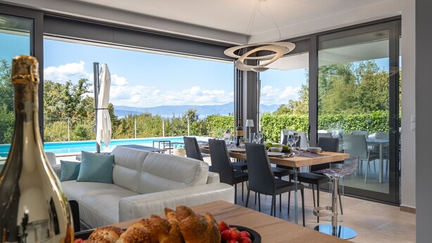 Un moderno comedor con vista a la piscina, un sofá y una mesa lista para comer.