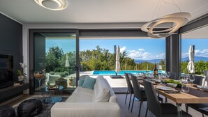 Una sala de estar moderna con un amplio ventanal corredizo que da a una zona de piscina.
