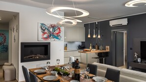 Un comedor moderno con una mesa de madera dispuesta para seis comensales, una chimenea y lámparas de diseño contemporáneo.