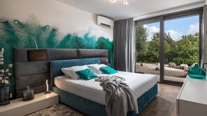 Une chambre moderne avec un grand lit, une table de chevet, une lampe et une vue sur l’extérieur.