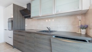 A modern kitchen with grey cabinetry, a stainless steel sink, and a built-in oven. - Villa Lara by Villas Guide (Kamenmost)
