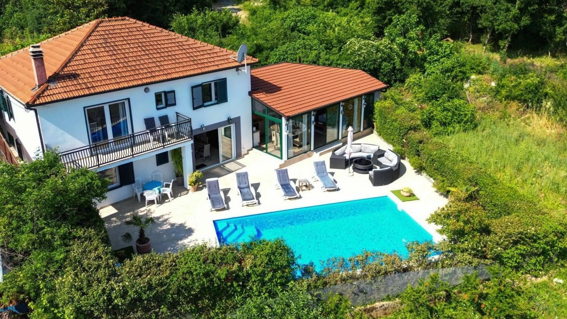 A two-story house with a swimming pool, a balcony, and a garden.