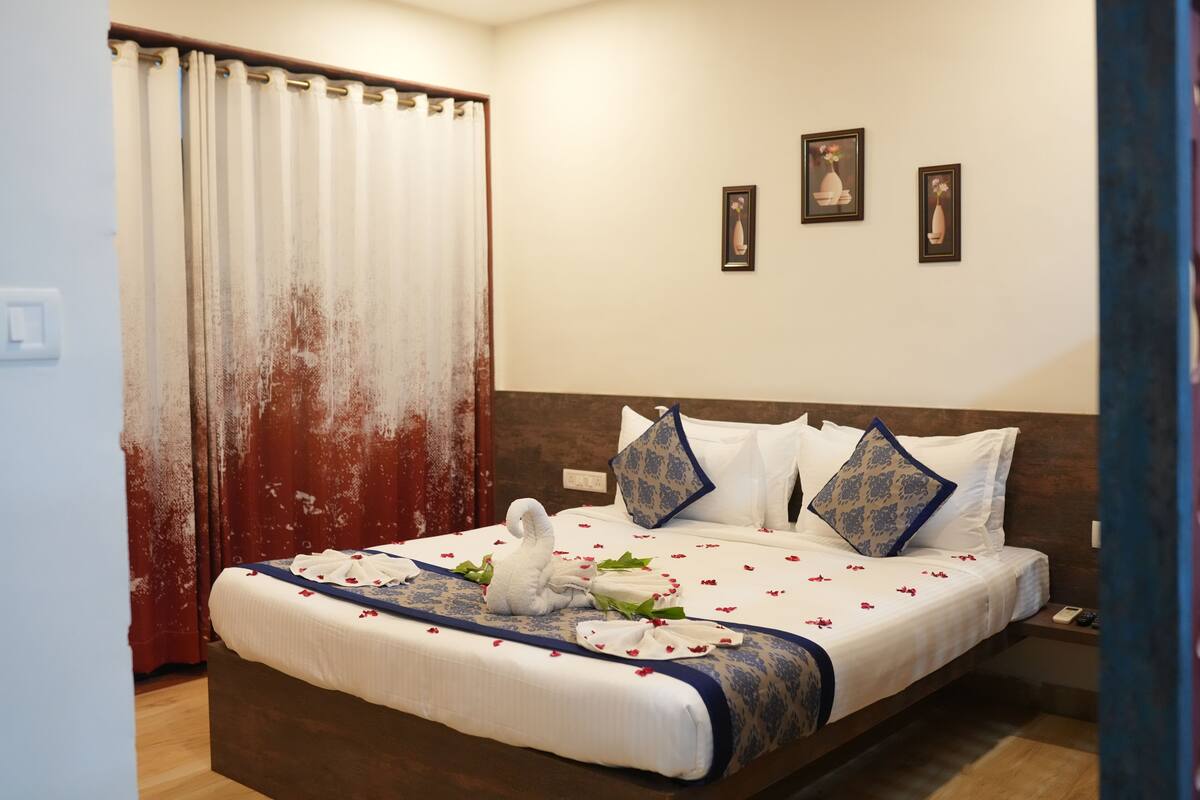 A neatly made bed with a blue and white bedspread, white pillows, and a decorative swan.