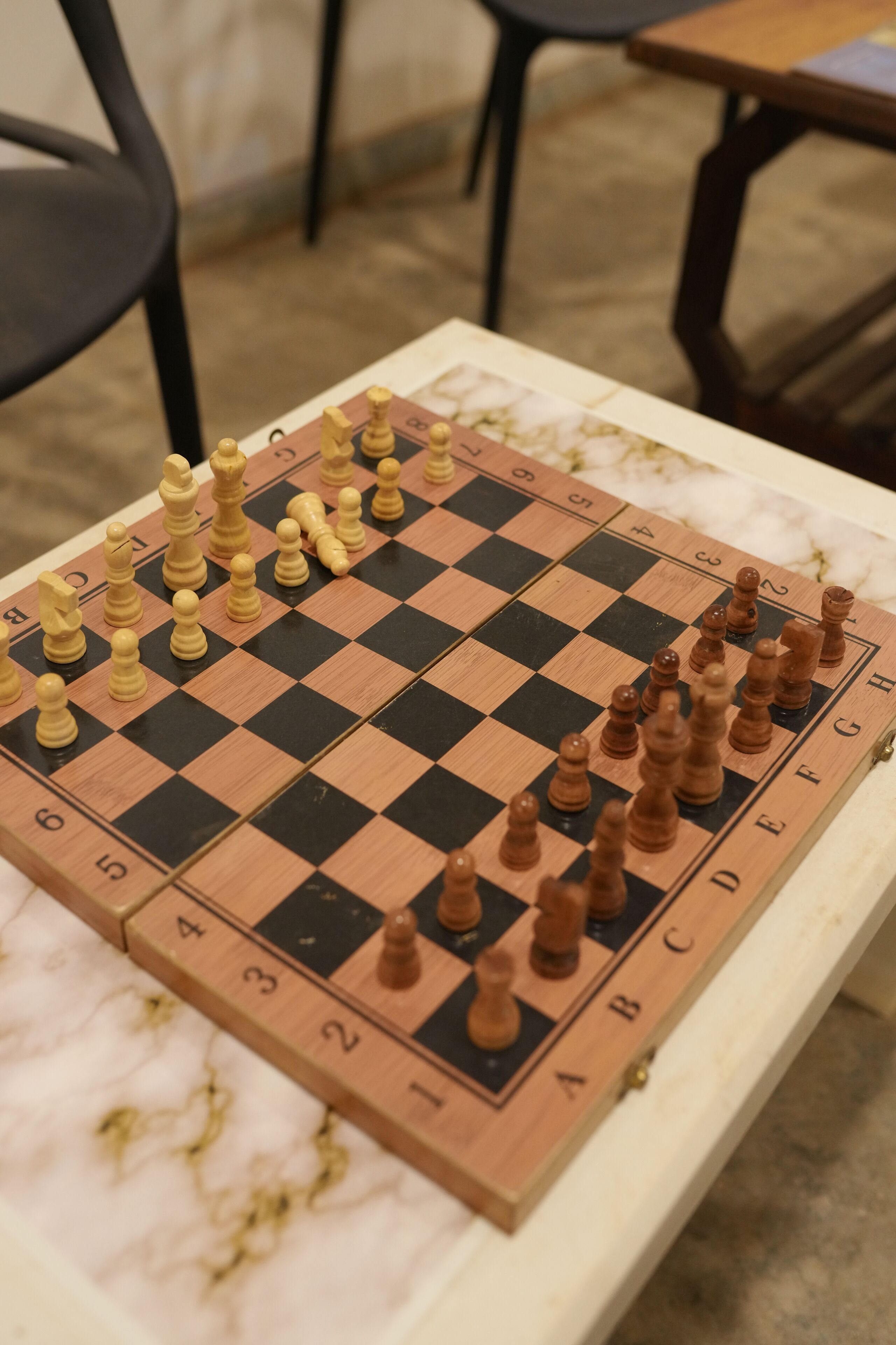 A chessboard on a marble table with a blurred background.