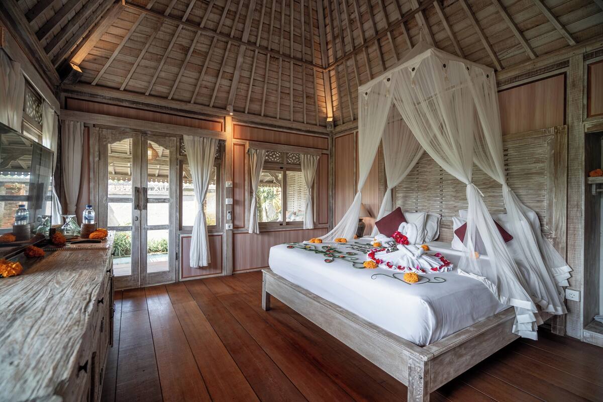 Une chambre spacieuse avec un grand lit, un plancher en bois et un lit à baldaquin.