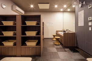 Un baño moderno con estantes de madera, cestas de mimbre, una zona de lavabo y un aire acondicionado de pared.
