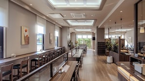 Un restaurant ampli amb sostres alts, llum natural que entra pels ulls de bou i diferents opcions d'asseients, com taules i seients privats.