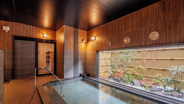 Una piscina interior moderna amb una paret de fusta i vista a un jardí de bambú.