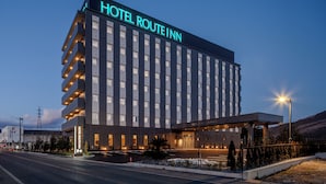 Un hotel de diverses plantes amb un senyal prominent que diu “HOTEL ROUTE INN”, un vestíbul cobert i una zona d'aparcament.
