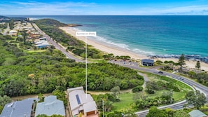 Uma área residencial à beira-mar, com praia, casas e uma estrada.