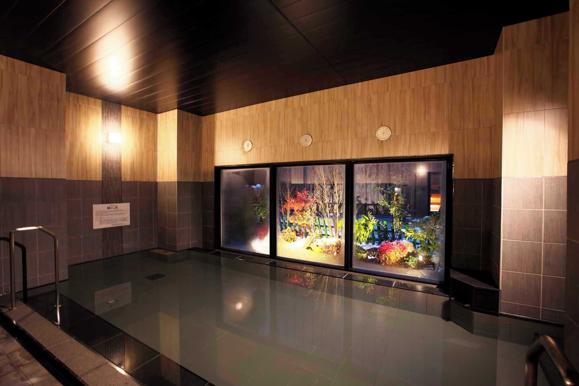 A modern indoor pool area with wooden paneling and glass walls.