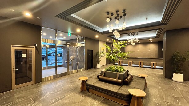 A modern lobby with a reception desk, seating area, and a large potted plant. - Hotel Route Inn Grand Fukushima Ekimae (Fukushima)