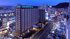A modern hotel with a prominent sign, multiple floors, and a parking area. - Hotel Route Inn Grand Fukushima Ekimae (Fukushima)