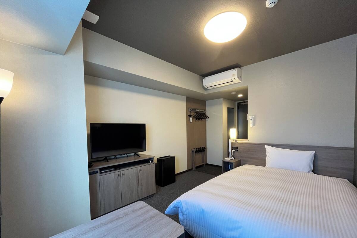 Une chambre d’hôtel équipée d’un lit, d’une télévision, d’un bureau et d’un appareil de climatisation.