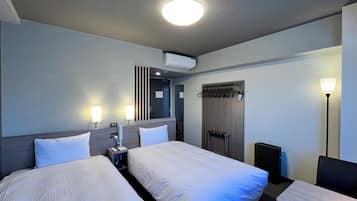 A hotel room with two beds, a desk, a chair, a lamp, a wardrobe, and a mirror.