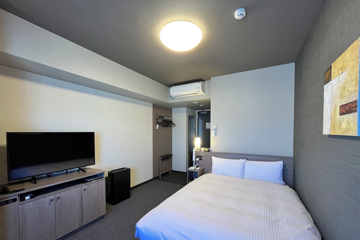 Une chambre d’hôtel équipée d’un lit, d’une télévision, d’un bureau et d’une armoire.