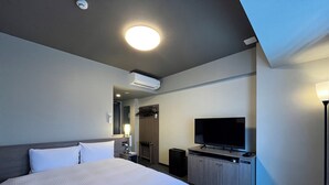 A hotel room with a large bed, a flat-screen TV, a desk with a computer, a wardrobe, and an air conditioning unit. - Hotel Route Inn Grand Fukushima Ekimae (Fukushima)