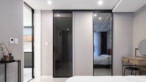 Een moderne slaapkamer met een groot bed, een houten bureau en een schuifdeur naar een badkamer.