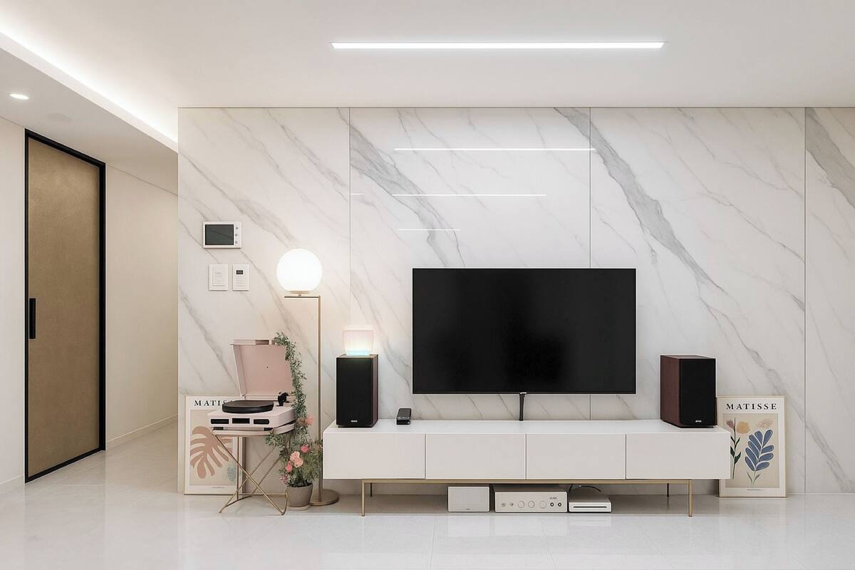 Un salon moderne avec un grand téléviseur à écran plat fixé sur un mur en marbre, un meuble de rangement blanc en dessous, et une petite table d’appoint avec une lampe et des objets décoratifs.