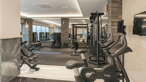 Een moderne sportschool met diverse fitnessapparaten, grote ramen en een ruimtelijke, schone indeling.