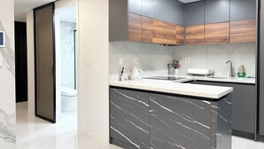 Een moderne keuken met een marmeren eiland, houten kasten en een wit aanrecht.