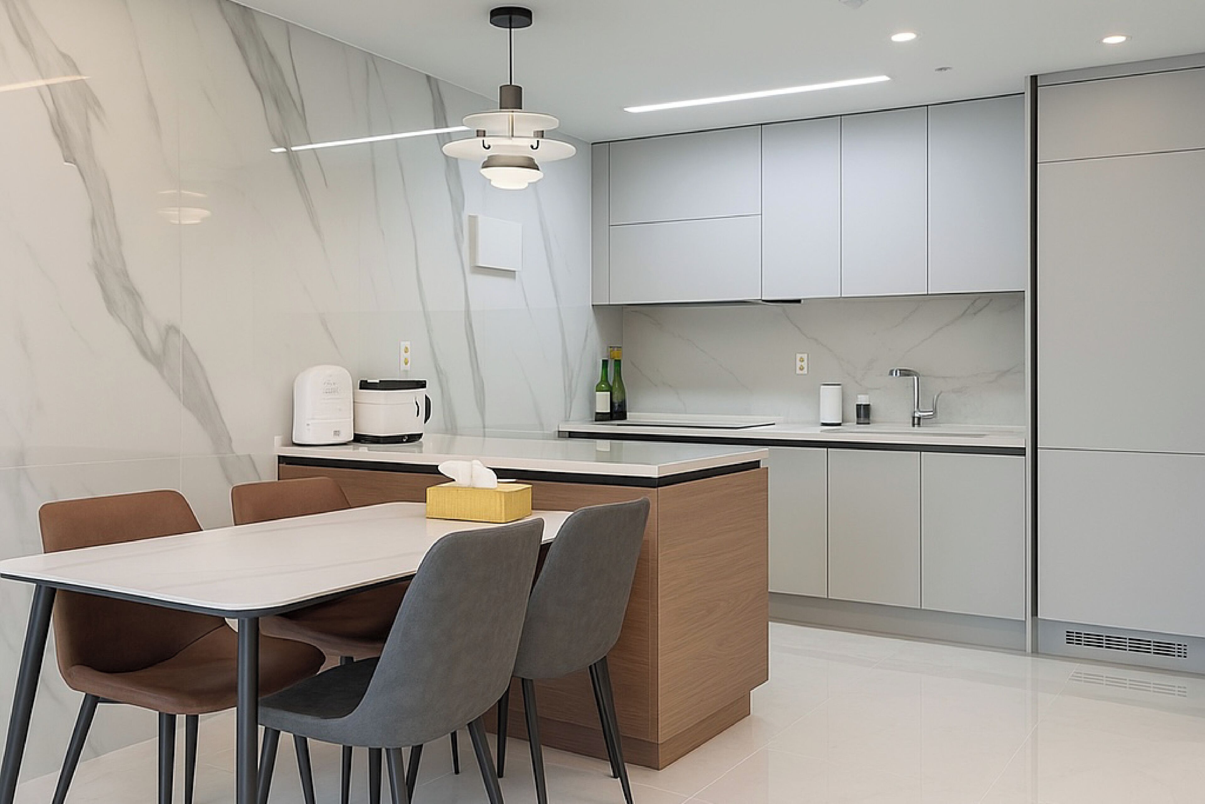 Una cocina moderna con armarios blancos, un protector contra salpicaduras de mármol y un comedor con mesa y sillas.