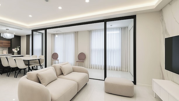 Een moderne woonkamer met een bank, een voetenbankje, een eethoek en een televisie.