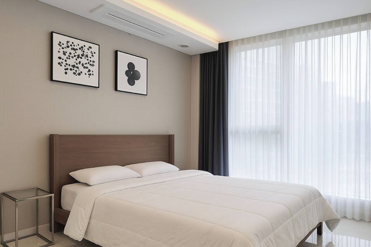 Une chambre d’hôtel moderne avec un grand lit, une table de chevet et deux œuvres d’art encadrées accrochées au mur.