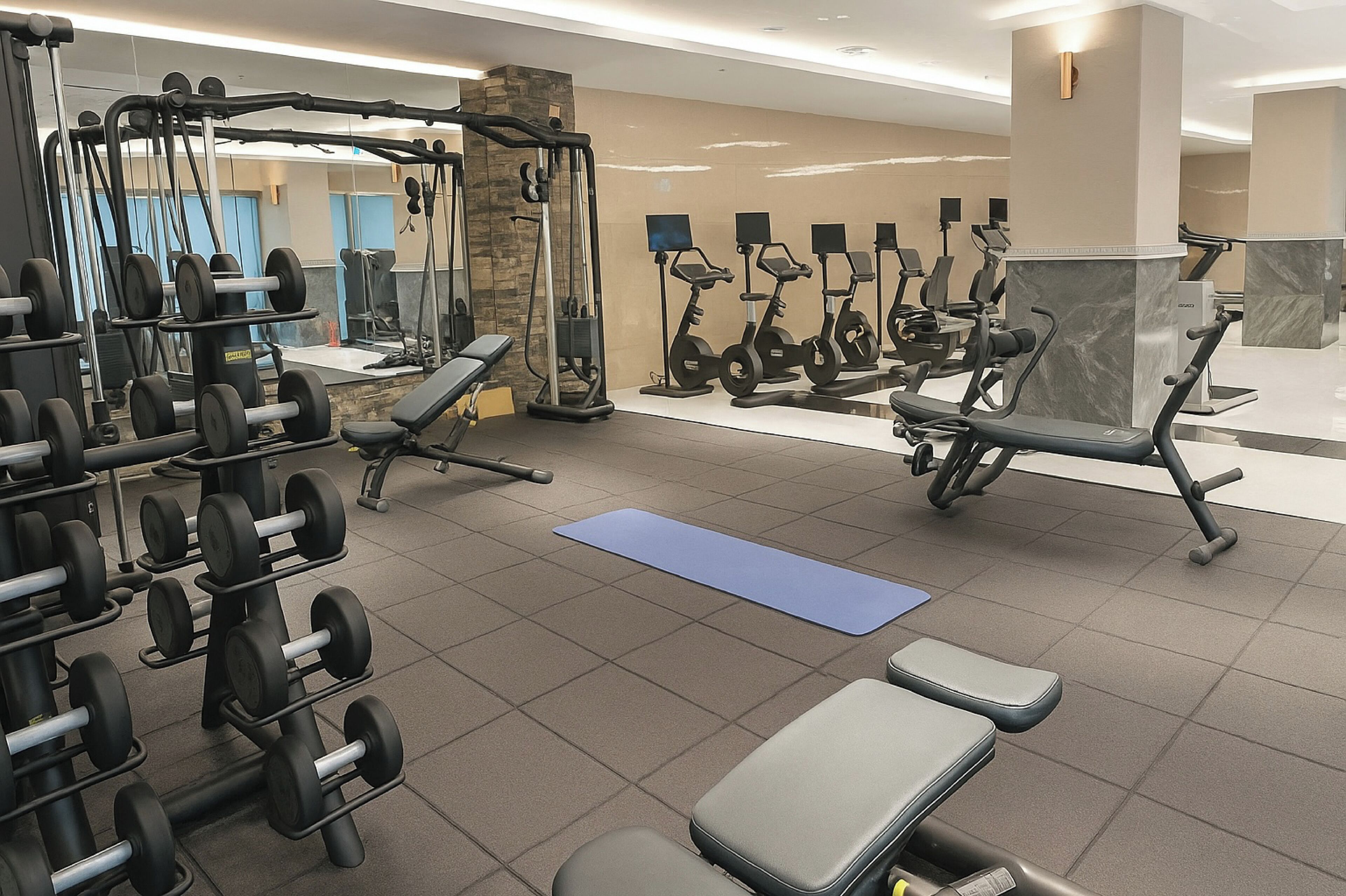 A gym with various exercise equipment, including dumbbells, a squat rack, and stationary bikes.