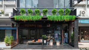 A modern hotel entrance with a seating area, potted plants, and a visible shop window. - Hotel 433 - Asoke Sukhumvit (Bangkok)