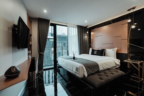 A modern hotel room with a large bed, a flat-screen TV, a desk, and a view of the city through large windows. - Hotel 433 - Asoke Sukhumvit (Bangkok)