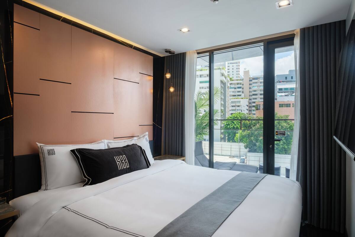 A modern hotel room with a large bed, a view of the city through the balcony, and a contemporary design.