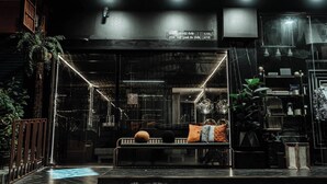 A modern hotel lobby with a glass partition, a reception desk, and a seating area with a bench and cushions. - Hotel 433 - Asoke Sukhumvit (Bangkok)