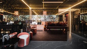A modern interior with a patterned wall, a sofa, a coffee table, and a red chair. - Hotel 433 - Asoke Sukhumvit (Bangkok)