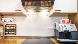 Cozinha equipada com fogão por indução embutido, máquina de café, prateleira para temperos e dispensador de toalhas.