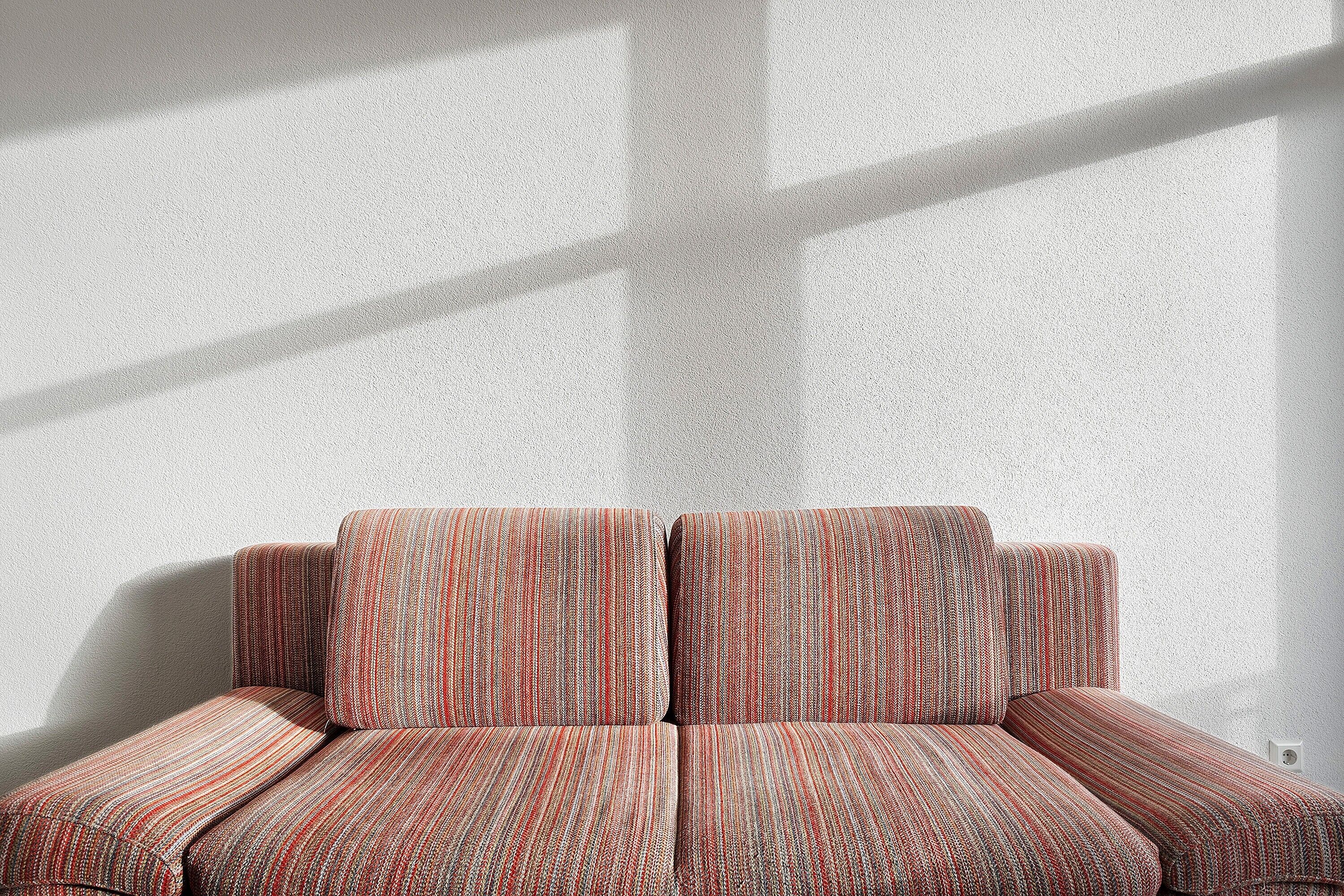 A sofa with a striped pattern against a plain wall.