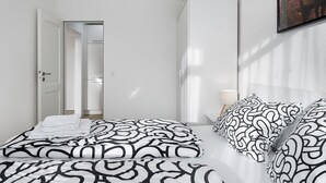 Een moderne hotelkamer met een net opgemaakt bed, een kledingkast en een ingelijste foto aan de muur.