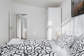 Une chambre d’hôtel moderne avec un lit bien fait, une armoire et un tableau encadré au mur.