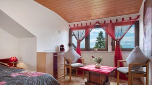 Un dormitorio con cama, escritorio, silla, mesa y ventana con cortinas.