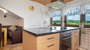 Una cocina con horno empotrado, un comedor con sofá y vistas a zonas verdes.