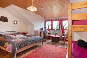 A bedroom with a bed, a desk, a chair, and a window with curtains.