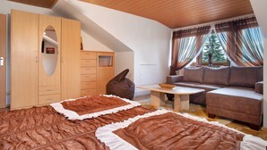 Una habitación con cama tipo altillo, un sofá, una mesa y un gran ventanal con cortinas.