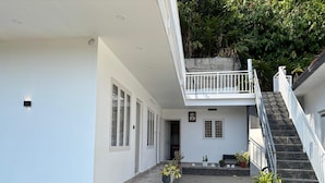 A modern building with a covered walkway, a staircase, and potted plants. - Aloha Homestay Munnar (Anachal)