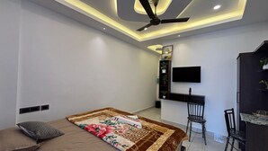 A modern bedroom with a bed, a desk, a chair, and a ceiling fan. - Aloha Homestay Munnar (Anachal)