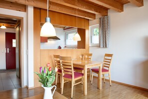 A dining area with wooden furniture, pendant lights, and a view of the kitchen.